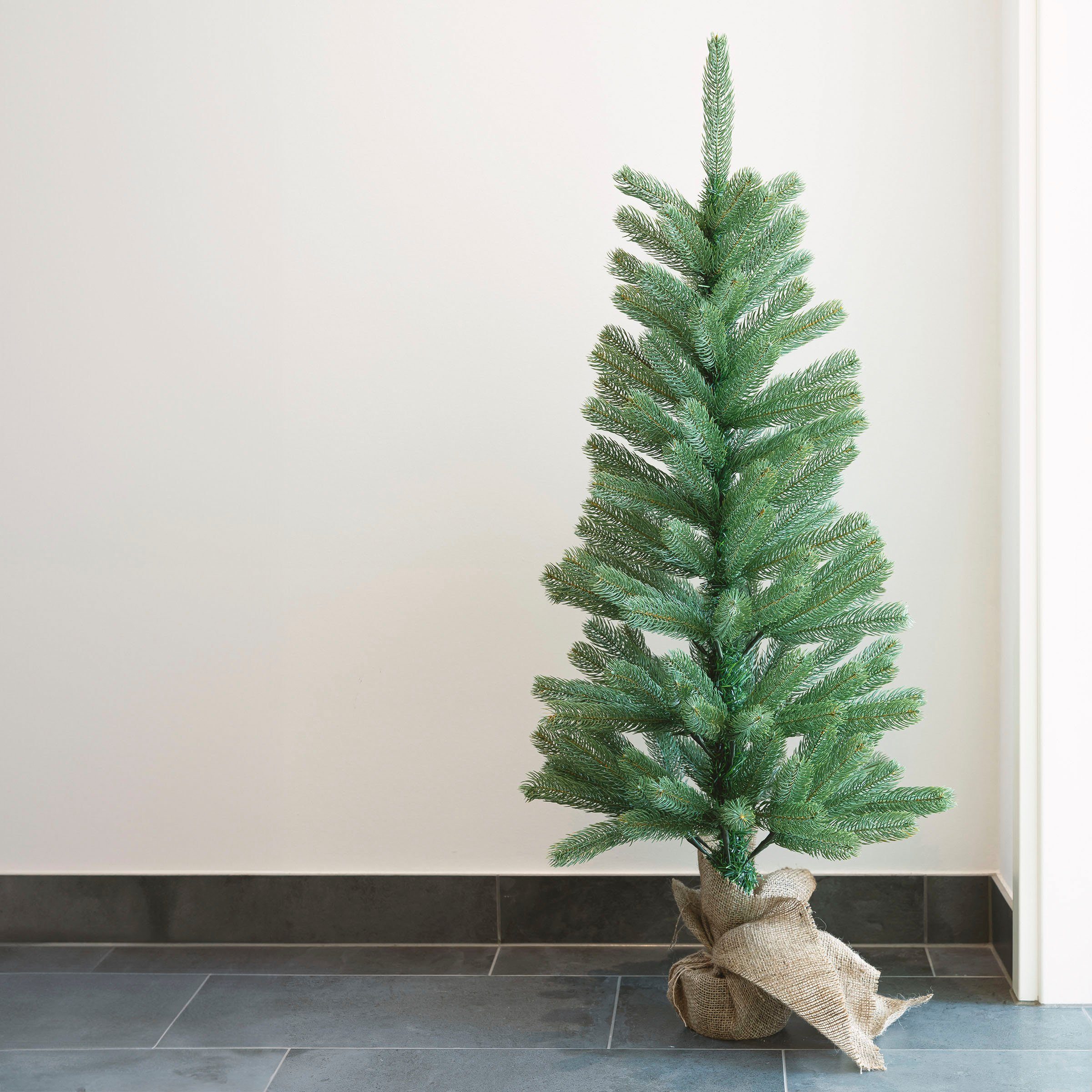 IC Winterworld Künstlicher Weihnachtsbaum Tannenbaum, künstlicher Christbaum, Nordmanntanne, Weihnachtsdeko mit Jutebeutel um den Betonfuß