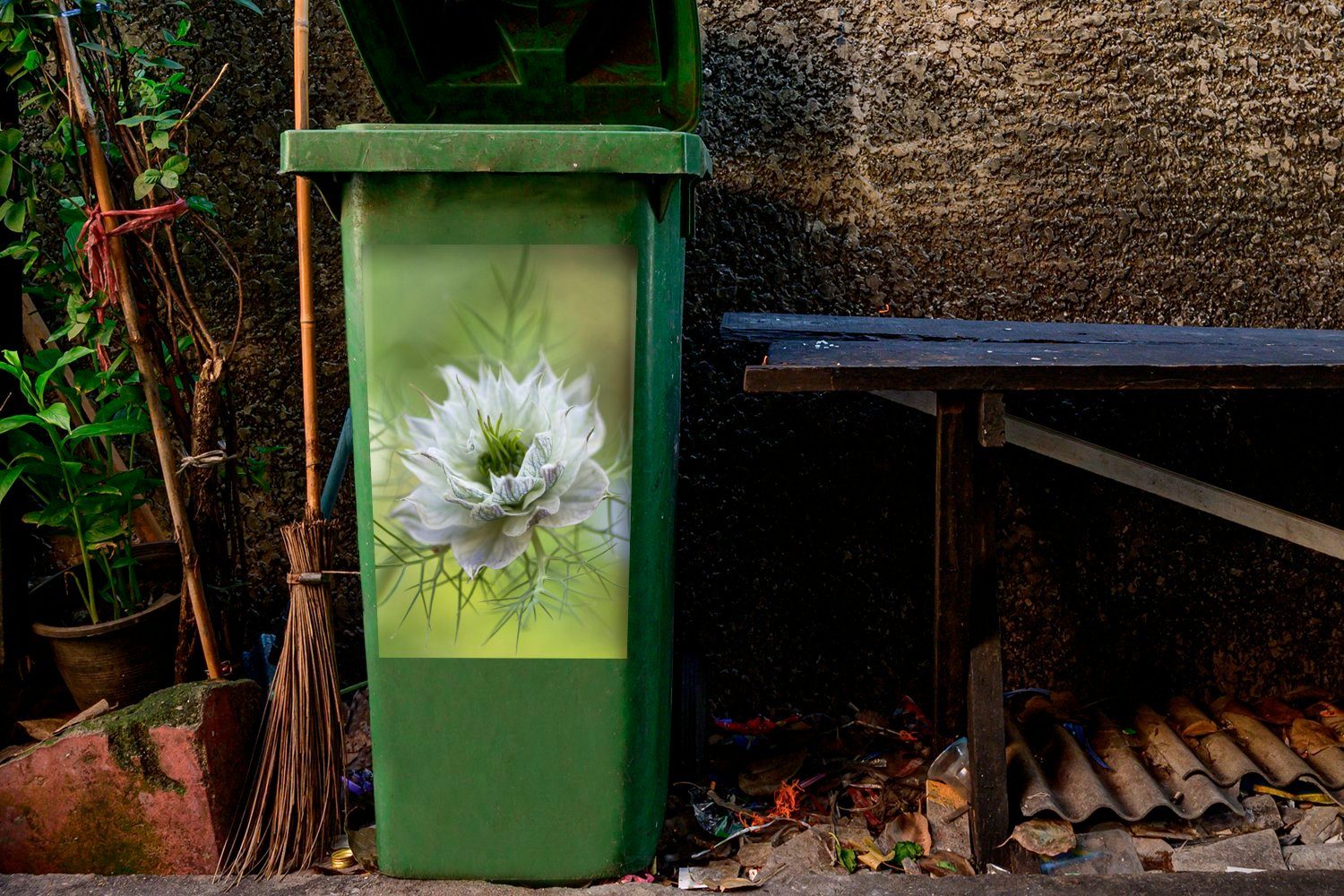 MuchoWow Wandsticker Eine Nigelblüte vor Container, grünem Abfalbehälter Mülleimer-aufkleber, (1 Sticker, Hintergrund St), Mülltonne