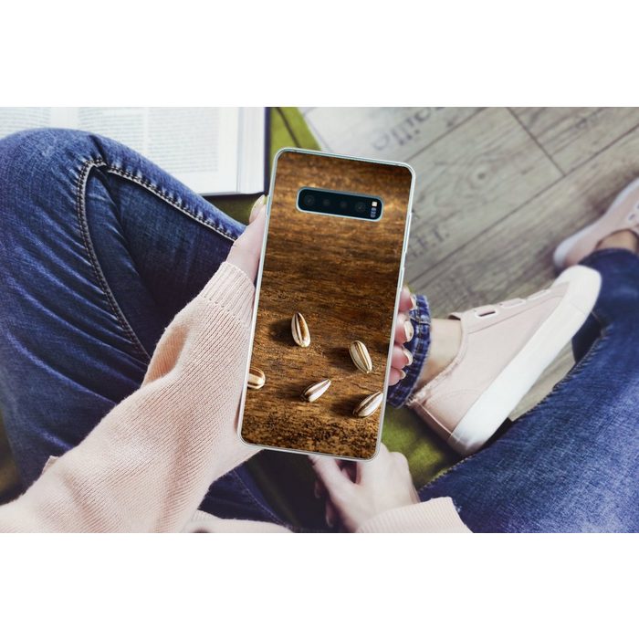 MuchoWow Handyhülle Zehn schöne Sonnenblumenkerne auf einem Holztisch Phone Case Handyhülle Samsung Galaxy S10+ Silikon Schutzhülle FN11475