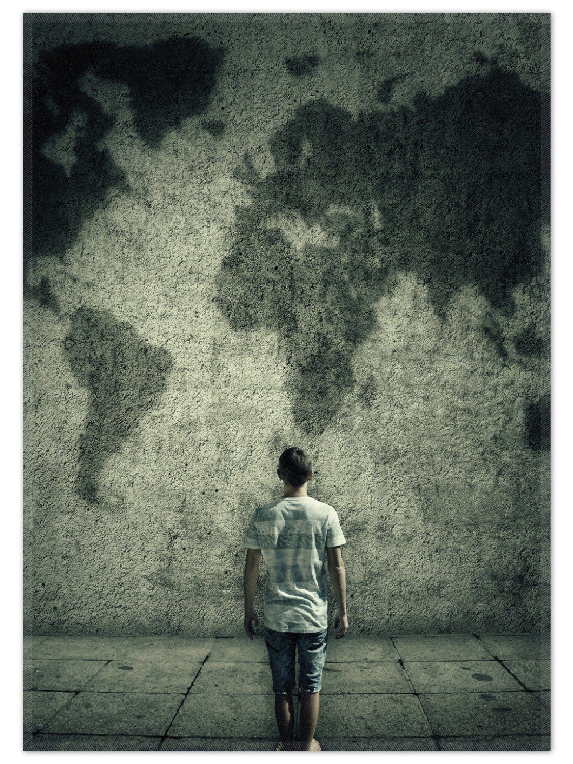 Wallario Teppich Kleiner Junge vor Weltkarte an grauer Beton-Wand, rechteckig, rutschfest