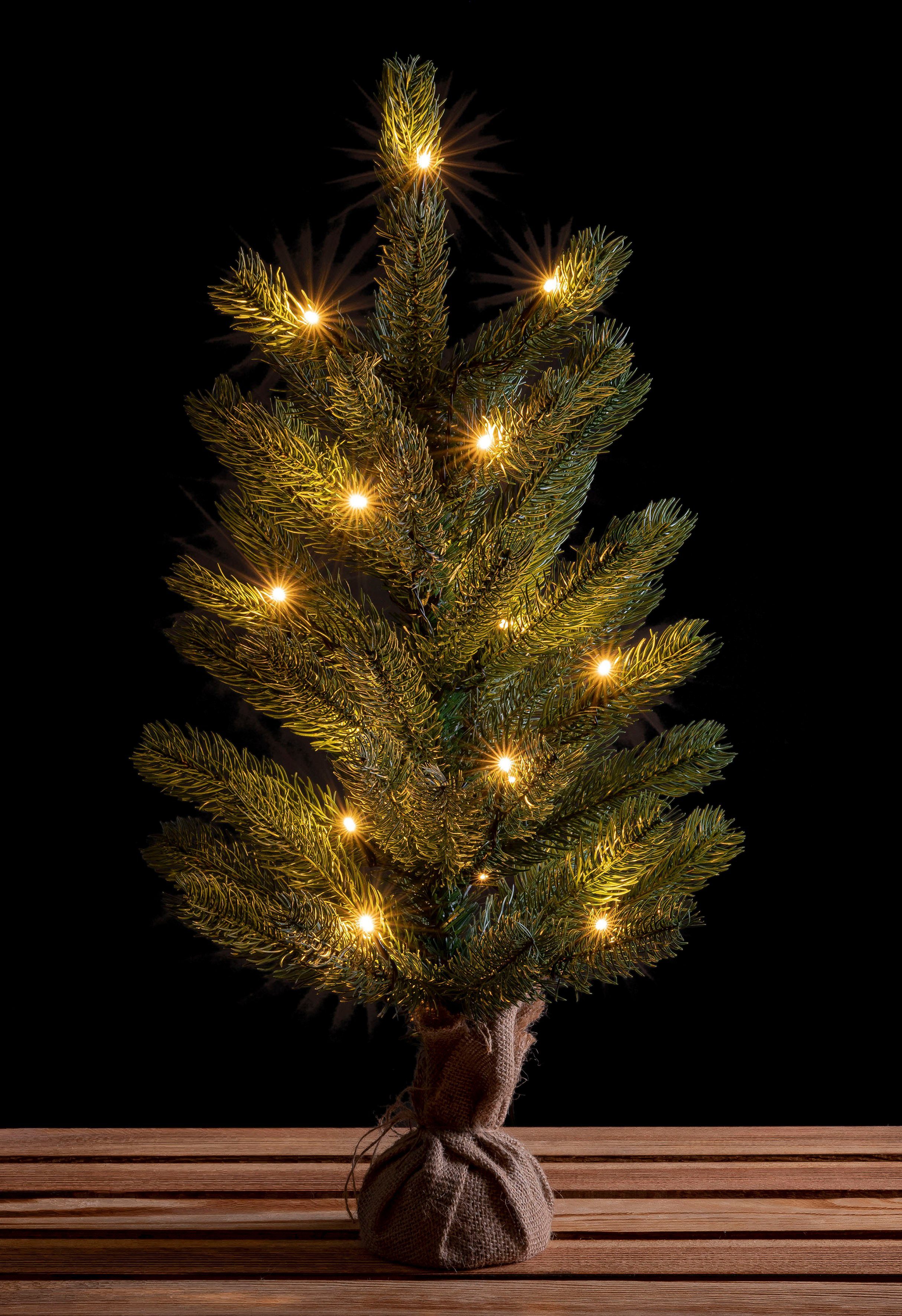 künstlicher Winterworld Weihnachtsbaum IC mit LED-Tannenbaum, 60 Weihnachtsdeko Christbaum, Nordmanntanne, ca. Künstlicher cm, Höhe Jutebeutel um Batteriebetrieb den Betonfuß,