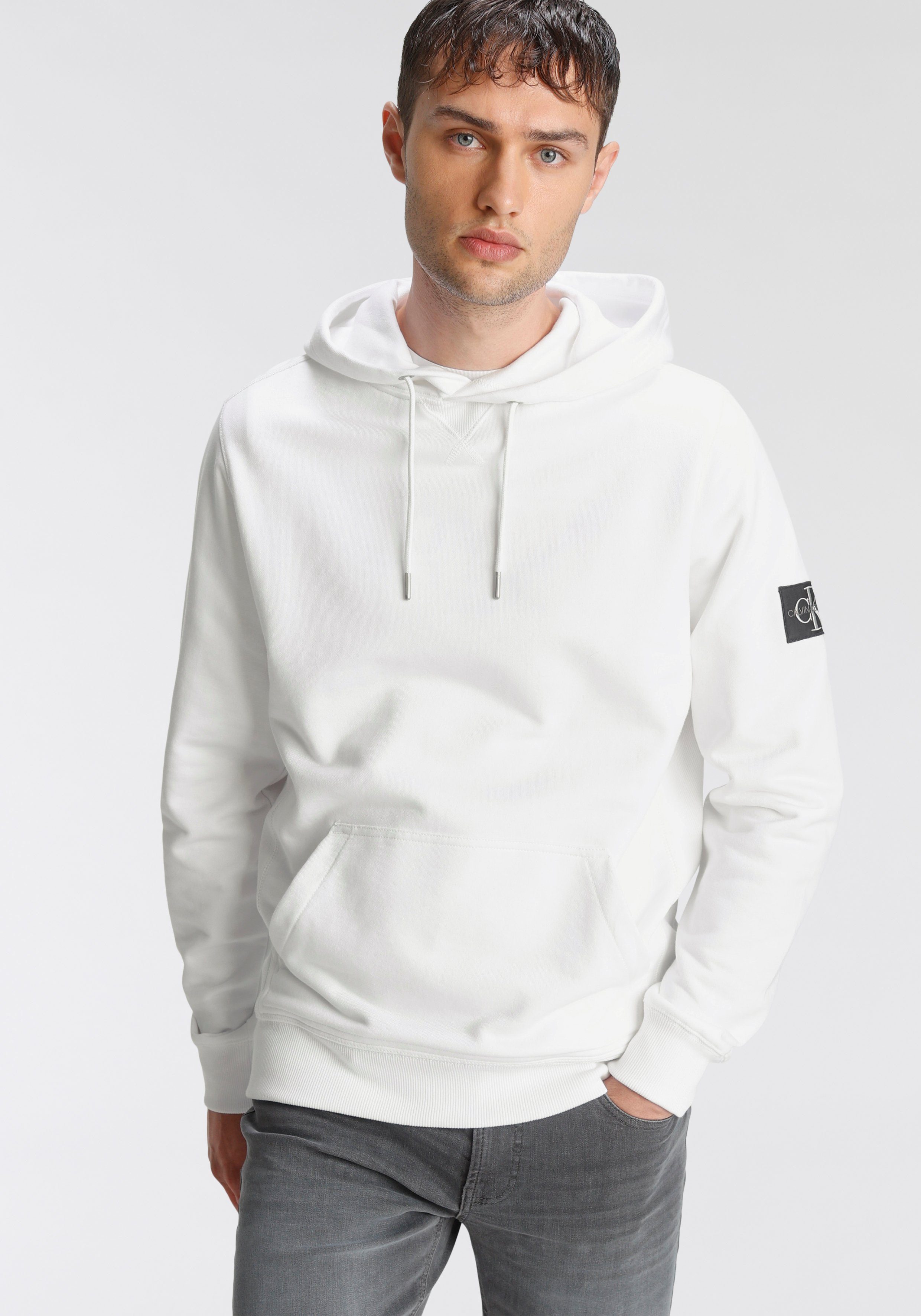 Calvin Klein Jeans Kapuzensweatshirt dem BADGE Ärmel YAF mit SLEEVE Bright MONOGRAM HOODIE White auf hochwertigem Markenbadge