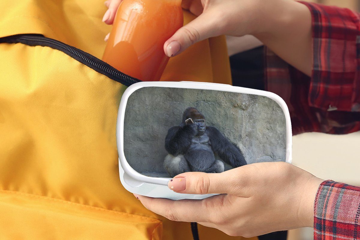 MuchoWow Lunchbox Ein riesiger Gorilla für lehnt weiß Brotdose, Jungs Mädchen Kinder Kunststoff, Erwachsene, (2-tlg), für an Brotbox einer und Steinmauer, und