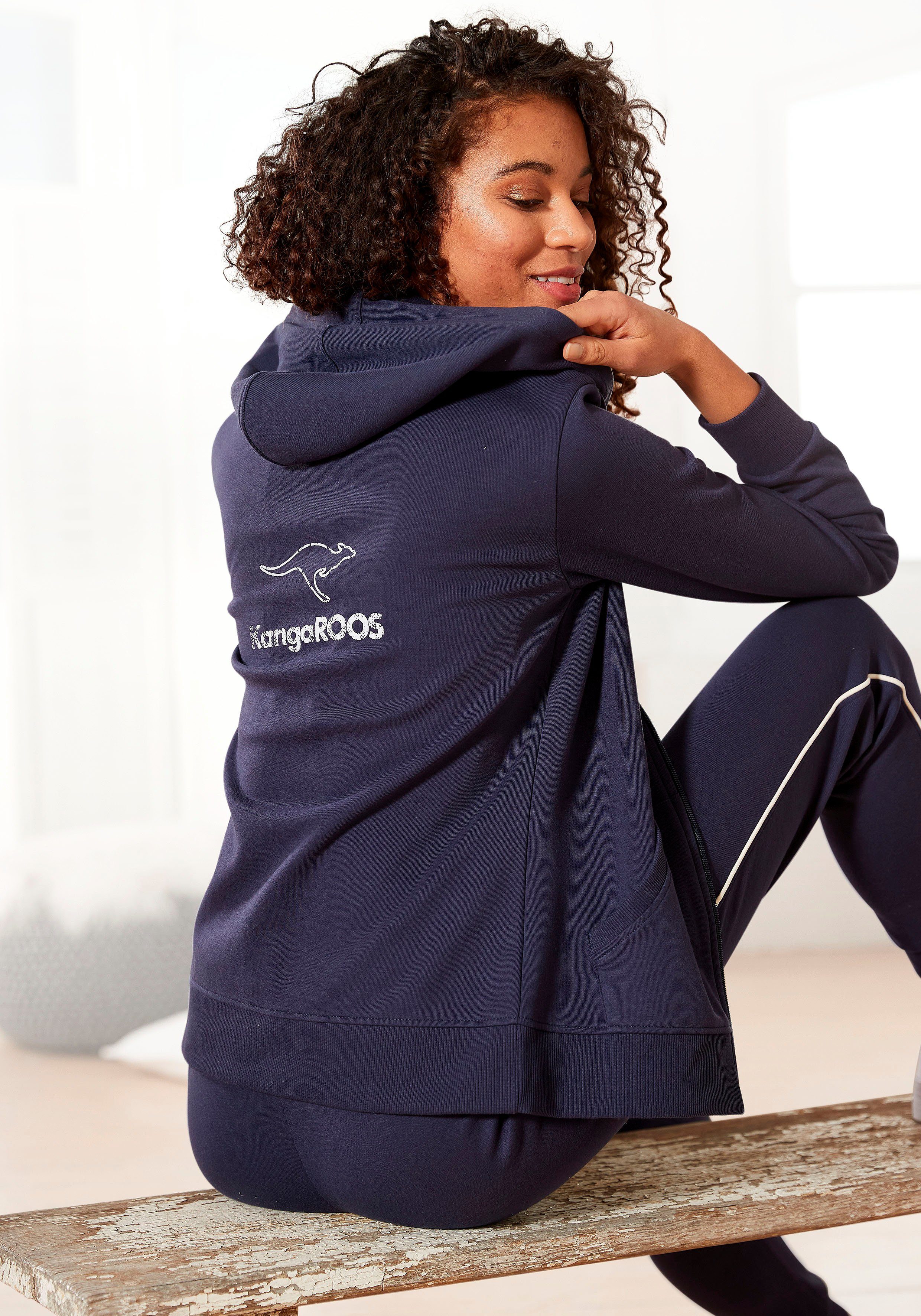 ist eine große Lagerräumung KangaROOS Sweatjacke mit Loungeanzug Rücken, großem auf Logodruck dem