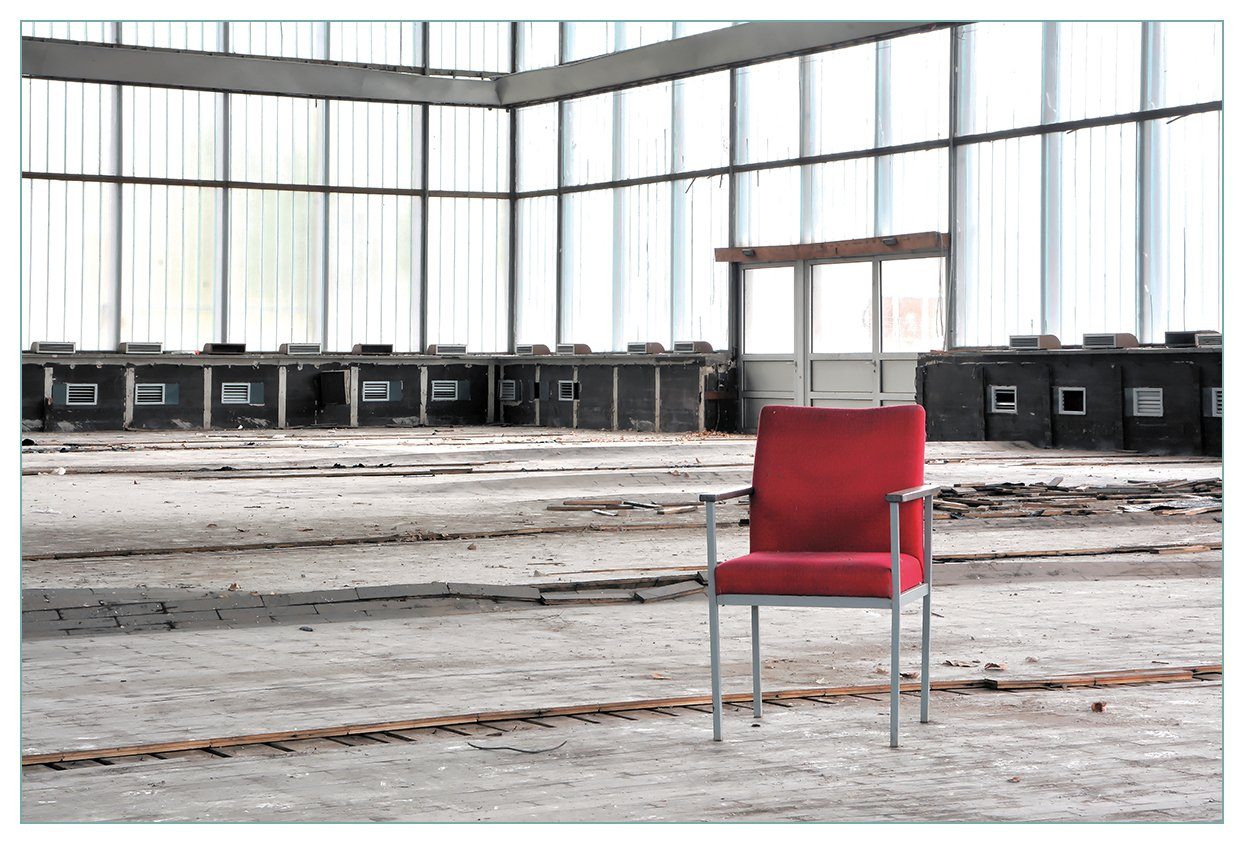 Wallario Küchenrückwand Stille und Leere - ein einsamer roter Stuhl in einer alten Halle, (1-tlg)