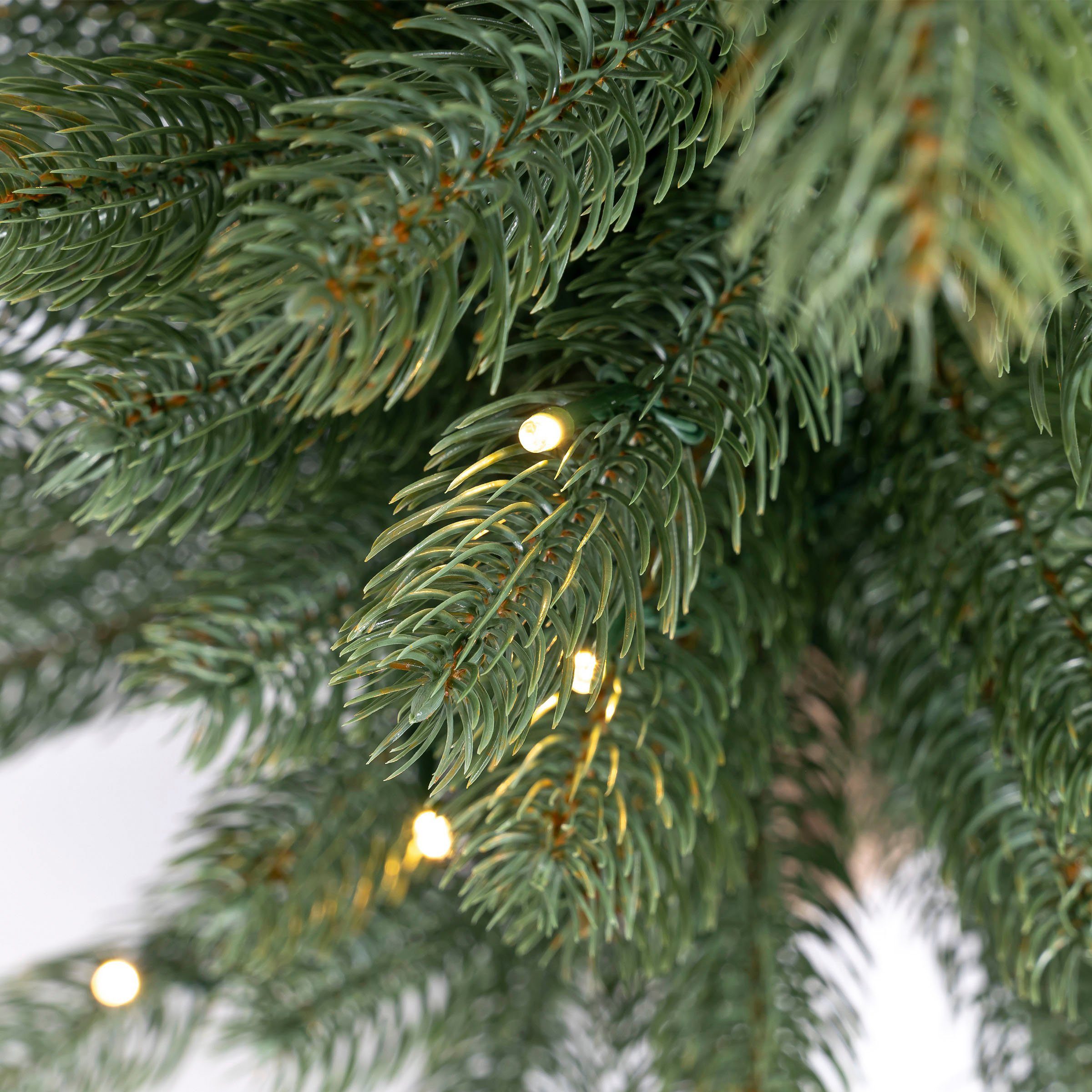 IC Winterworld Künstlicher Weihnachtsbaum LED-Tannenbaum, künstlicher Christbaum, Nordmanntanne, Weihnachtsdeko mit Jutebeutel um den Betonfuß, Batteriebetrieb