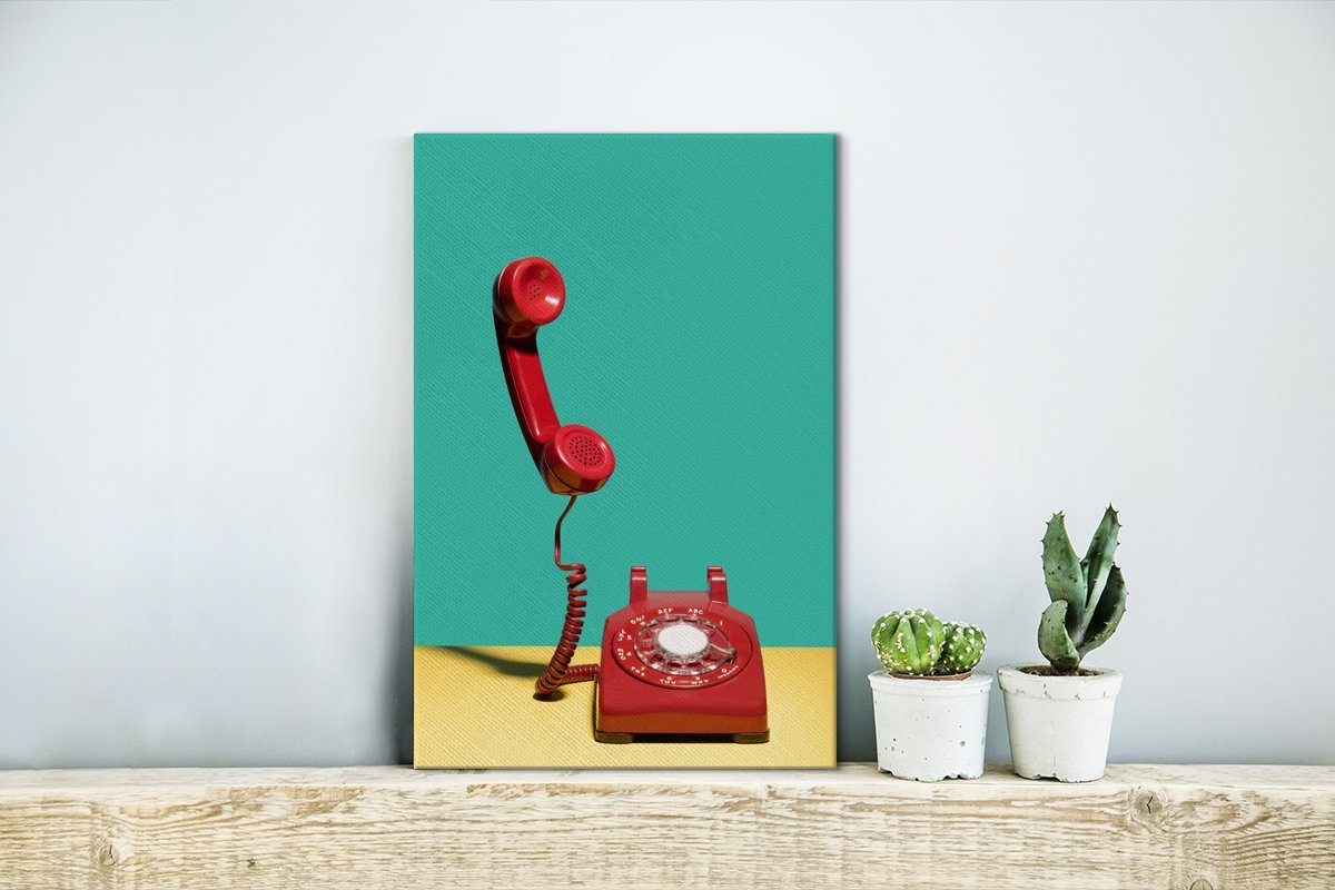 OneMillionCanvasses® Leinwandbild Ein rotes Leinwandbild St), Gemälde, fertig Zackenaufhänger, einer vor cm Wand, bespannt Retro-Telefon (1 grünen inkl. auf 20x30 gelbem Hintergrund