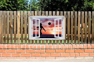 Wallario Sichtschutzzaunmatten Fußball - Kleiner Junge spielt im Abendrot, mit Fenster-Illusion