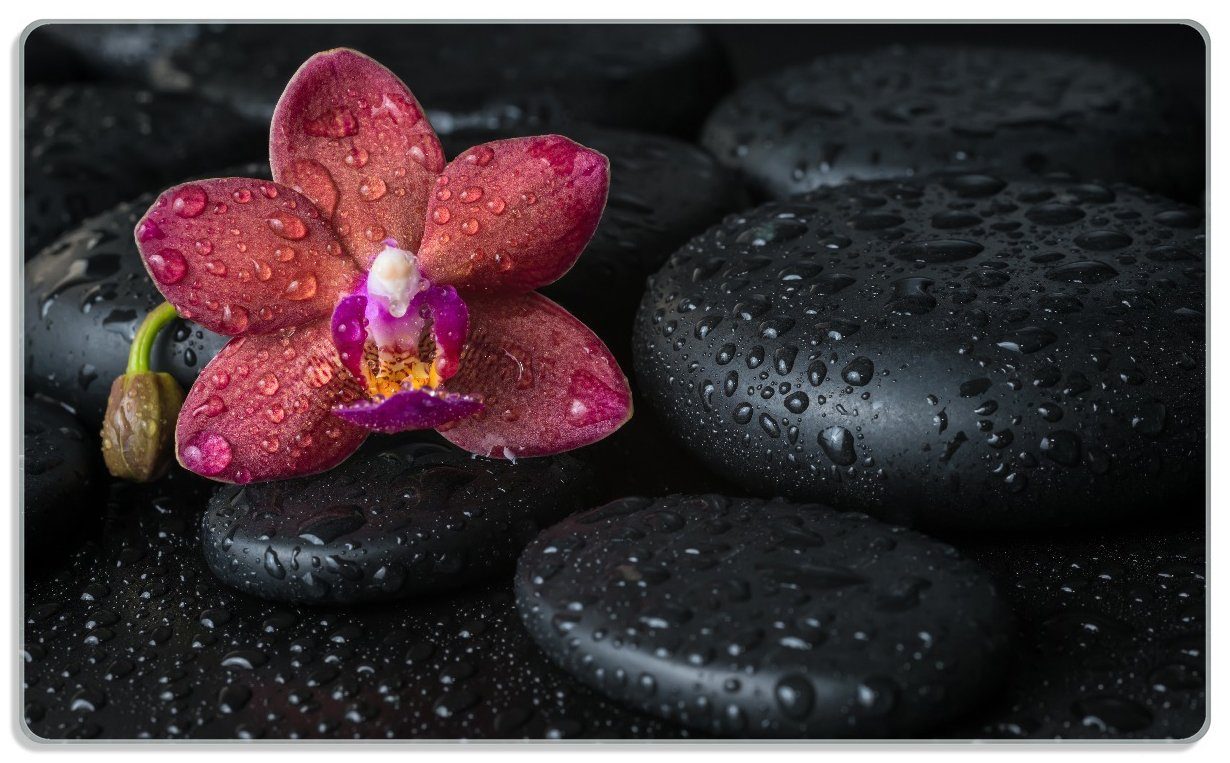Wallario Frühstücksbrett Orchideen-Blüte auf schwarzen Steinen, benetzt mit Wasser-Tropfen, ESG-Sicherheitsglas, (inkl. rutschfester Gummifüße 4mm, 1-St), 14x23cm