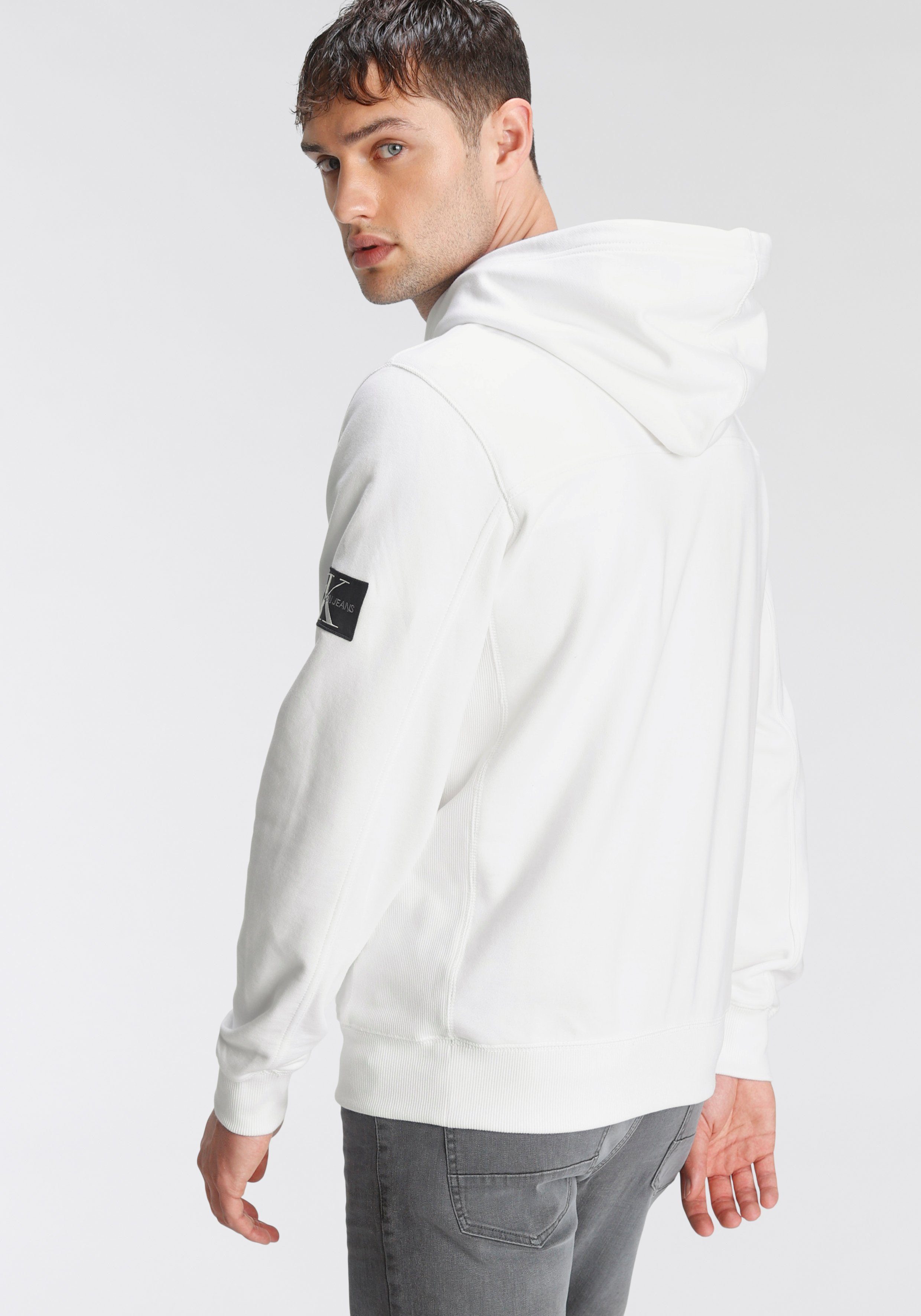 Calvin Klein Jeans Kapuzensweatshirt dem BADGE Ärmel YAF mit SLEEVE Bright MONOGRAM HOODIE White auf hochwertigem Markenbadge