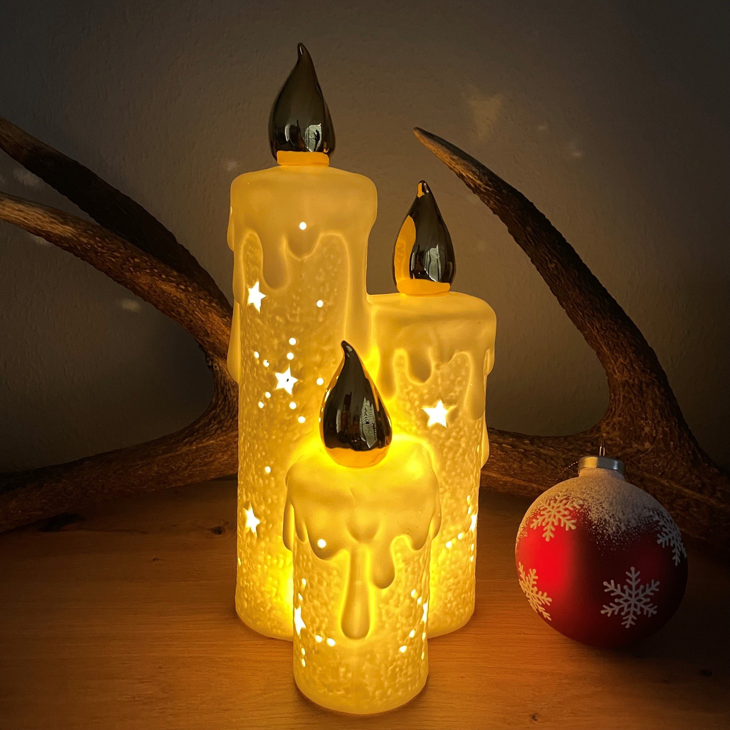 Online-Fuchs LED Dekoobjekt als 3 verschmolzene Kerzen-Optik aus Keramik  mit LED Beleuchtung 202, LED fest integriert, goldene Flamme, warmweiß,  Maße: 28x12x12 cm, ausgestanzte Sterne und Schneeflocken