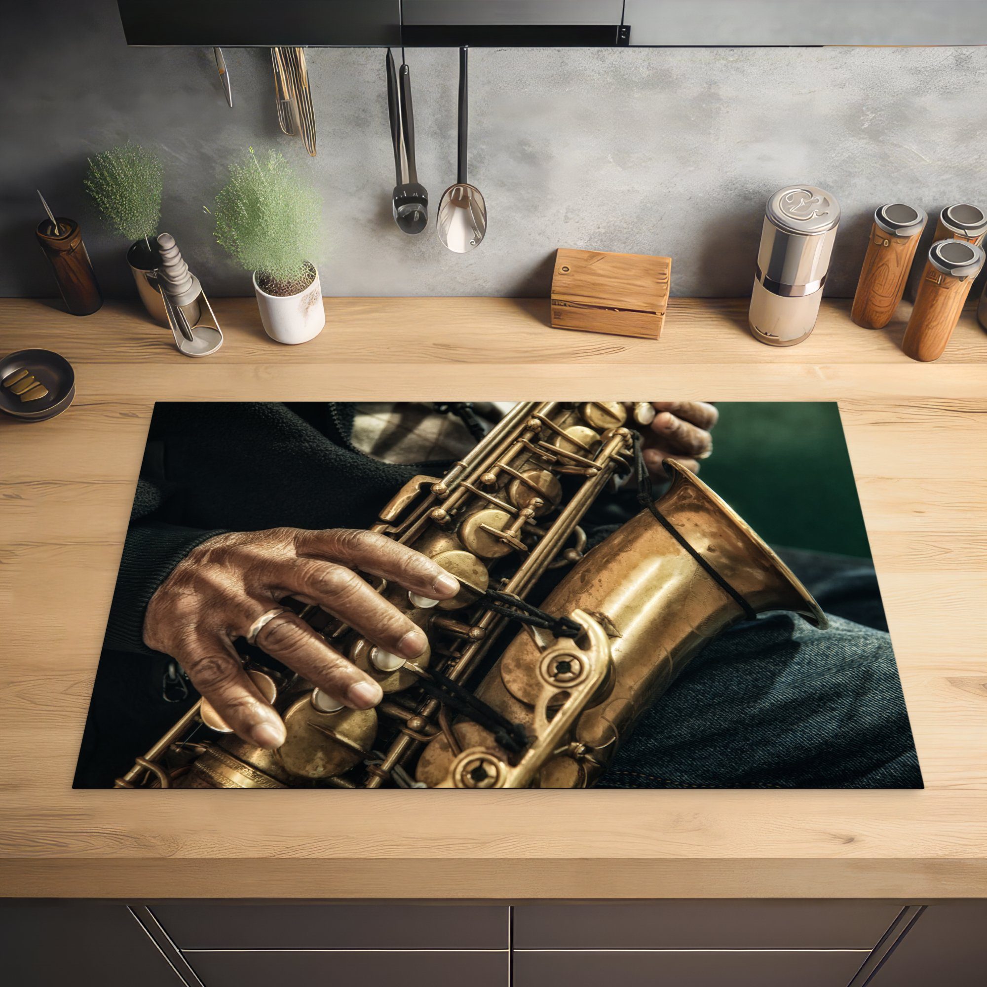 Hand einem MuchoWow Saxophon, einer die Herdblende-/Abdeckplatte 81x52 tlg), cm, Vinyl, Induktionskochfeld auf (1 küche, Schutz Ceranfeldabdeckung Nahaufnahme für