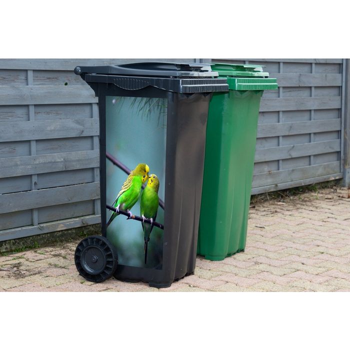 MuchoWow Wandsticker Zwei leuchtend grüne Sittiche auf einem Ast (1 St) Mülleimer-aufkleber Mülltonne Sticker Container Abfalbehälter