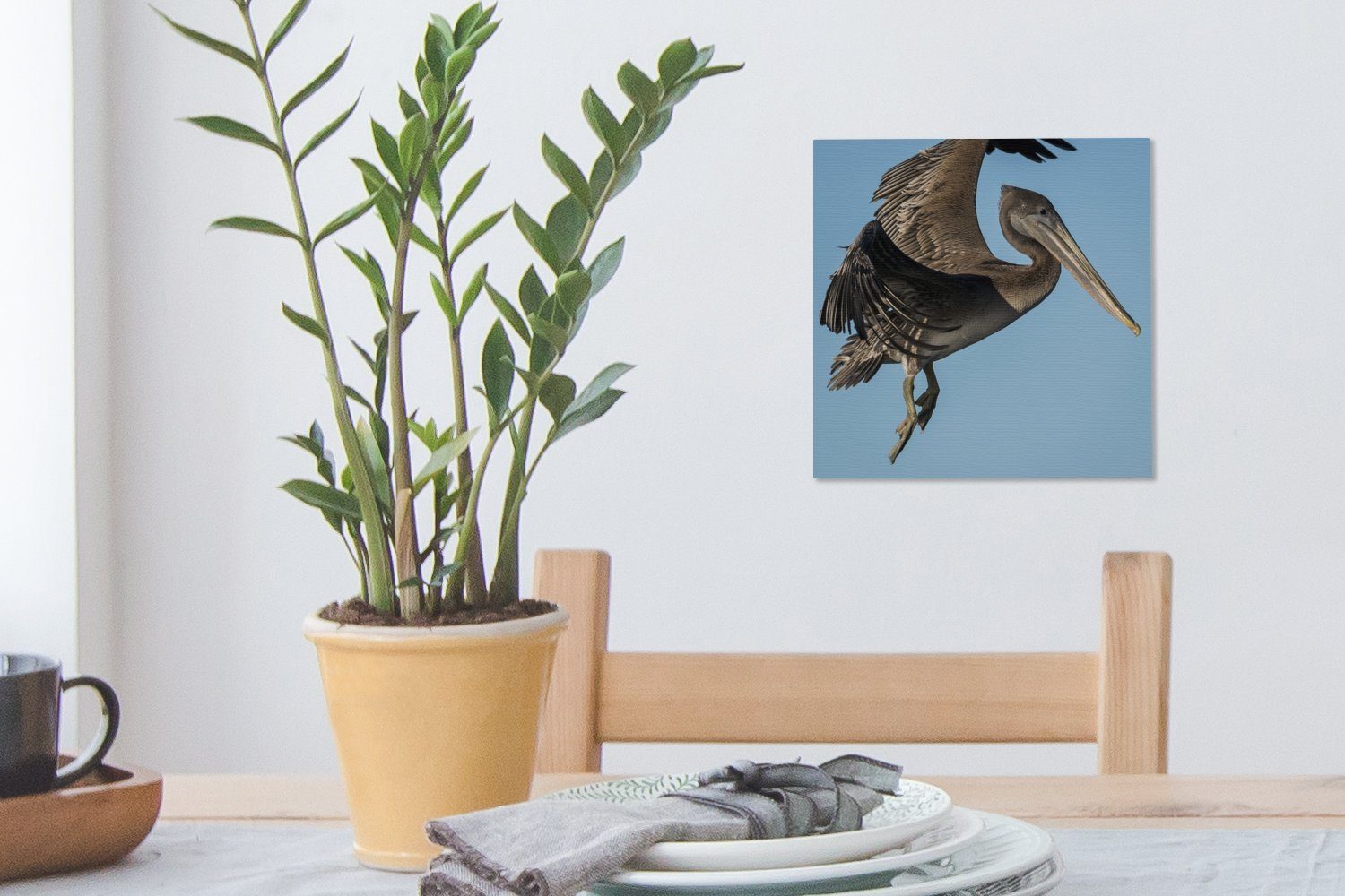 OneMillionCanvasses® Leinwandbild Ein brauner den (1 Himmel, blauen für Leinwand Pelikan fliegt Schlafzimmer Bilder in St), Wohnzimmer