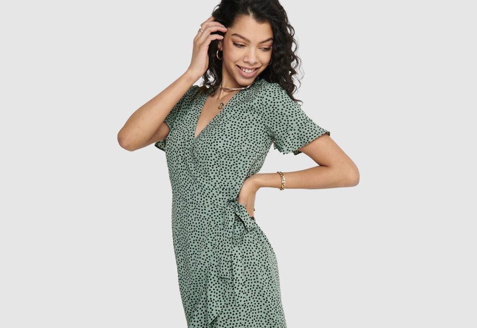 Frau in gemustertem Sommerkleid auf grauem Hintergrund